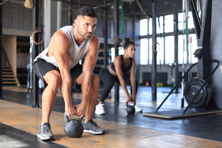 Canadian man lifting a kettlebell in a gym after eating Hummzies Hummus Sticks